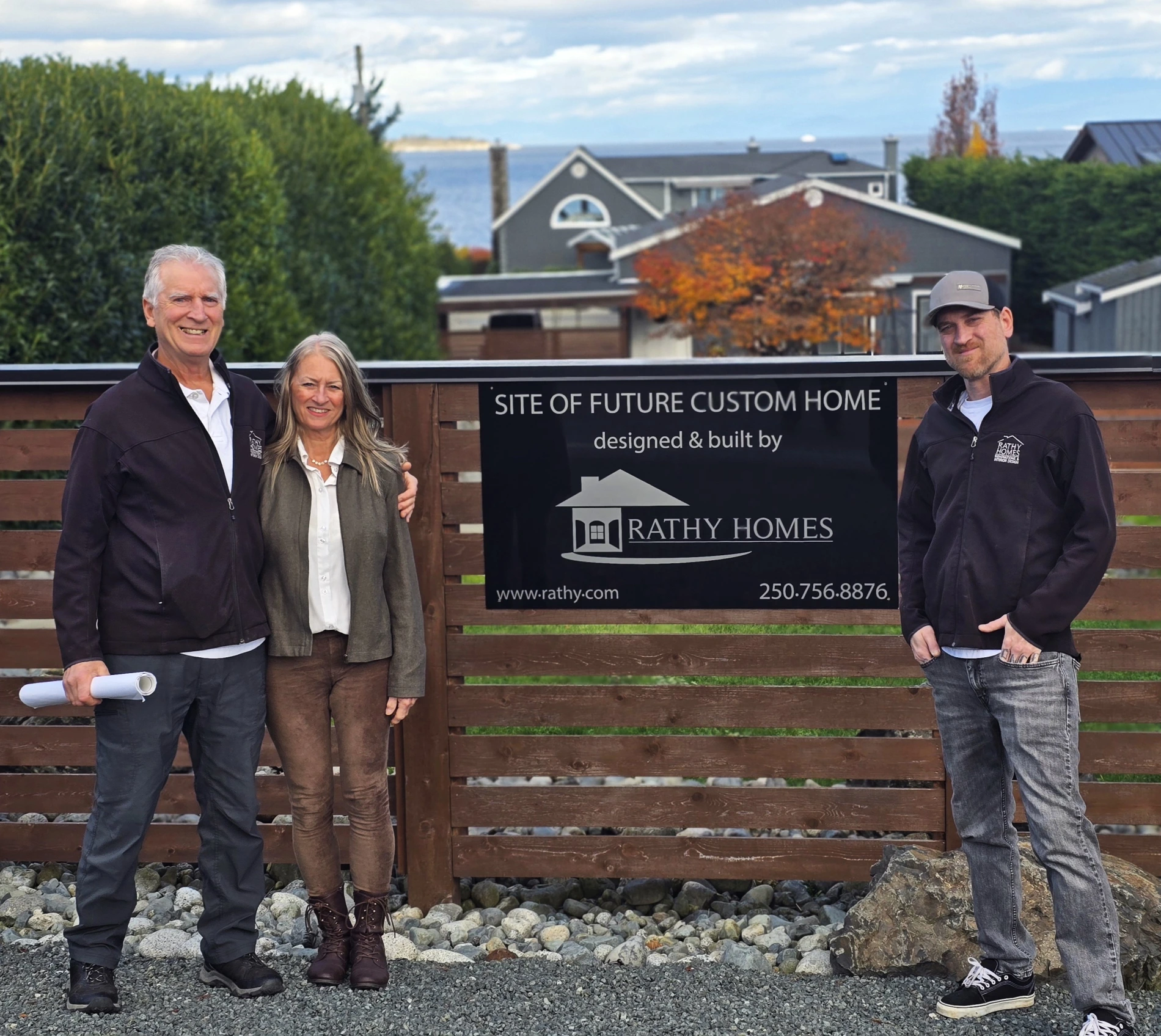 Doug Rathy, Ruth Rathy, and Pierce Rathy standing together beside a company-branded sign